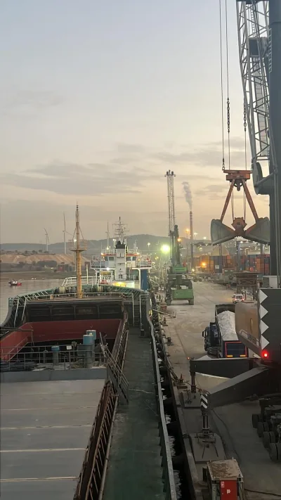 Mobile harbour crane with an open grab working alongside at dusk, raw salt in bulk, M/V Gold Lucky, Izmir → Izmail