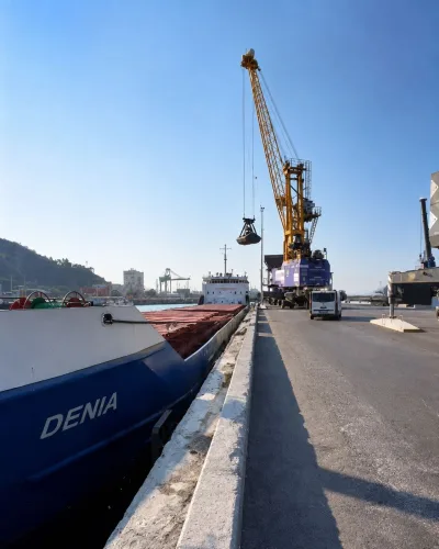 岸壁のコースターをグラブ付き陸上クレーンで荷役