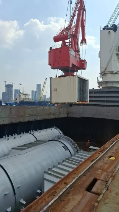 Shore crane lifting a crated unit over the hold above stowed gas turbine casings, Siemens gas turbines, Niigata → Qingdao