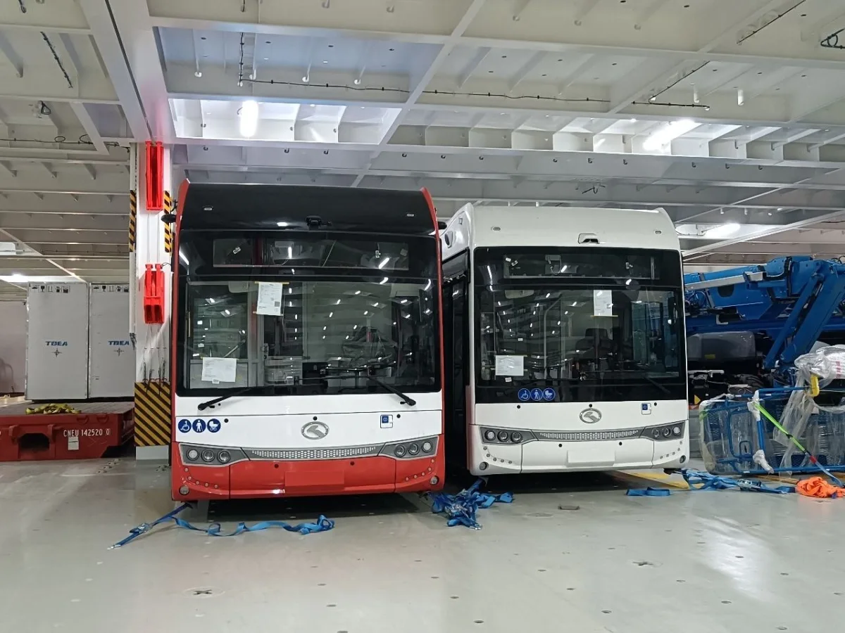 Two electric buses with lashing straps on a vessel's vehicle deck